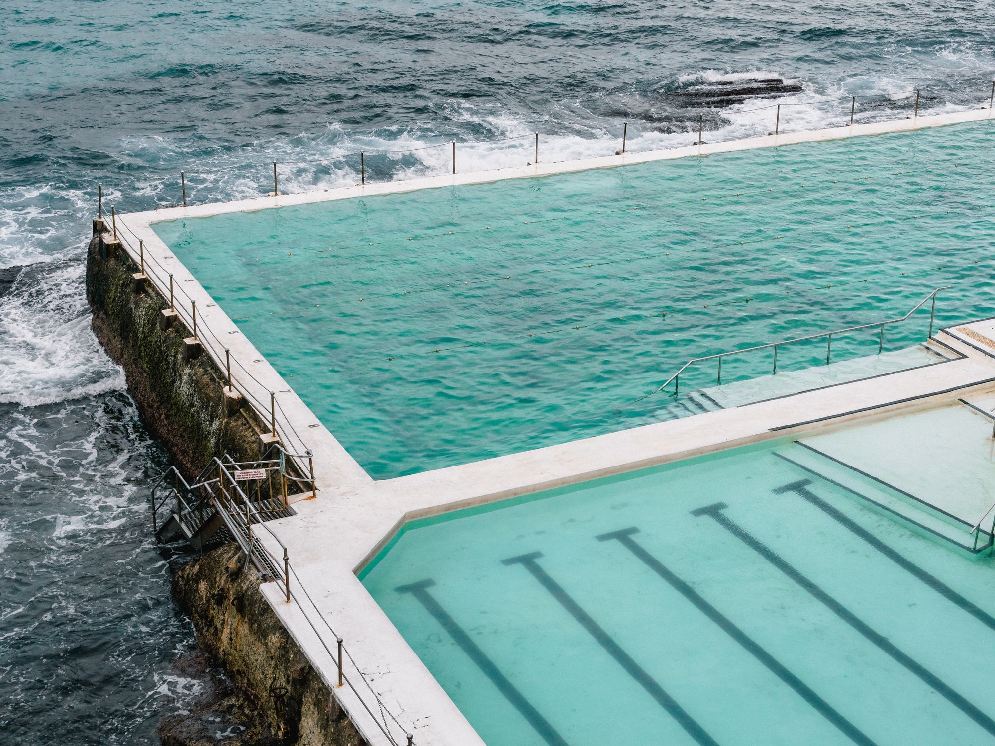 Bondi Icebergs ocean pool from the air, with waves breaking over the wall